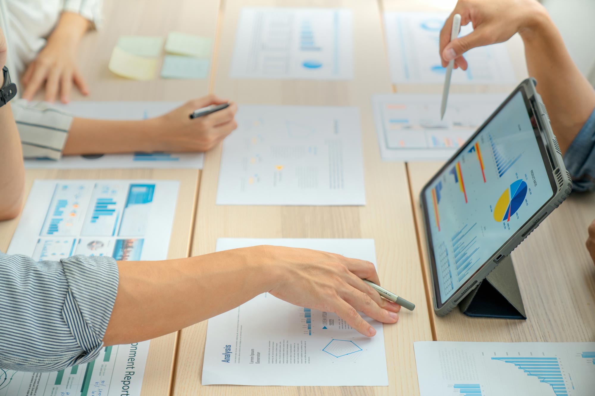 Närbild av affärskollegor som analyserar finansiella data vid bordet på moderna kontor om affärsstrategier.